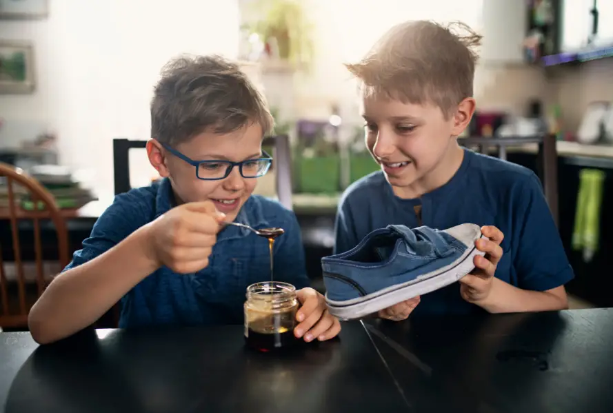 Two boys putting syrup in someone's shoe