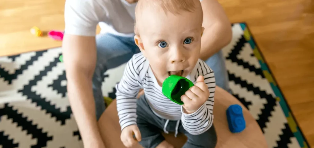 a baby holding putting a toy on his mouth